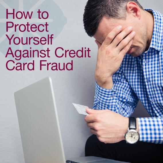 Man with head in hands holding a credit card in front of a laptop