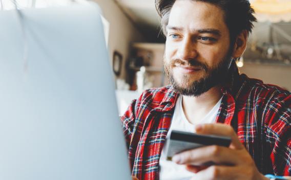 a man uses a credit card with his computer