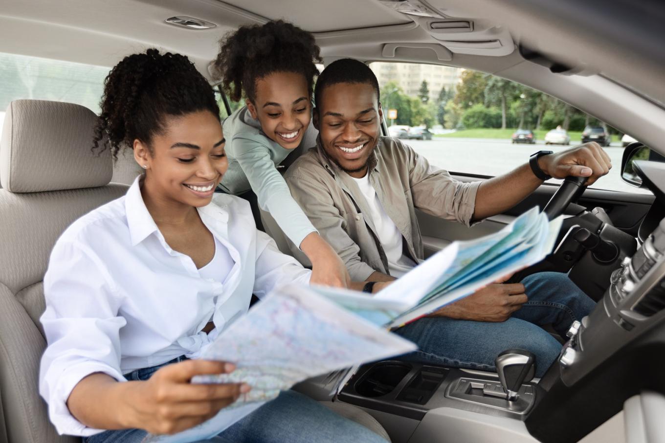 Happy family in a car looking at a map