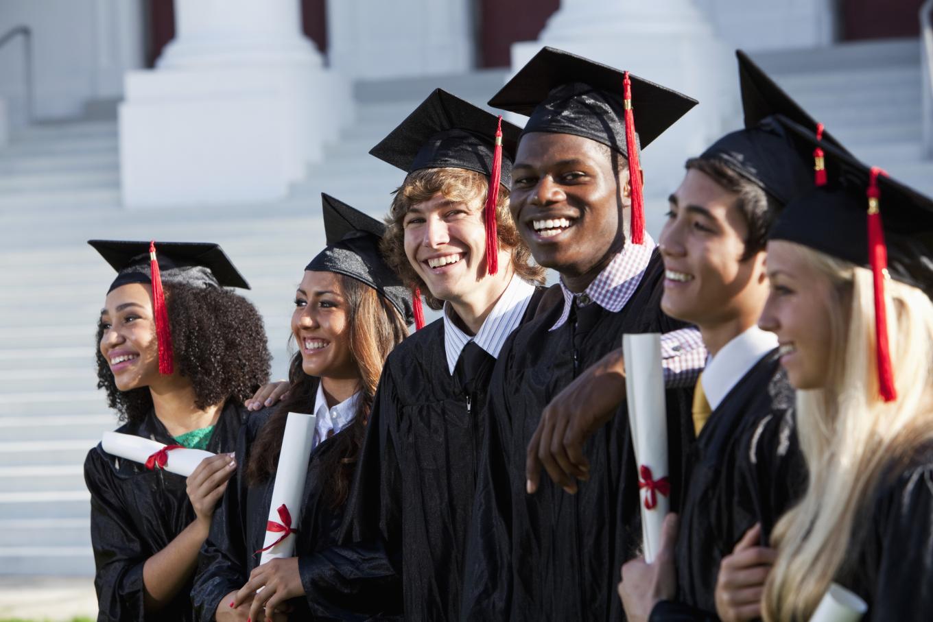 Happy Graduates in cap and gown holding diplomas