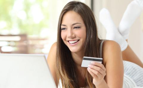 Shopper shopping online with credit card and laptop on the bed at home