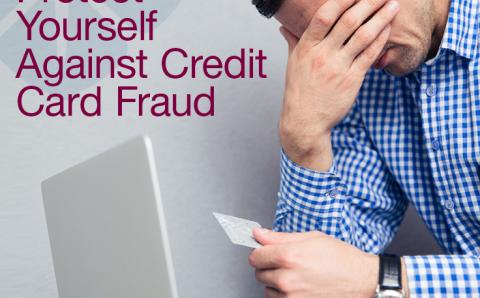 Man with head in hands holding a credit card in front of a laptop