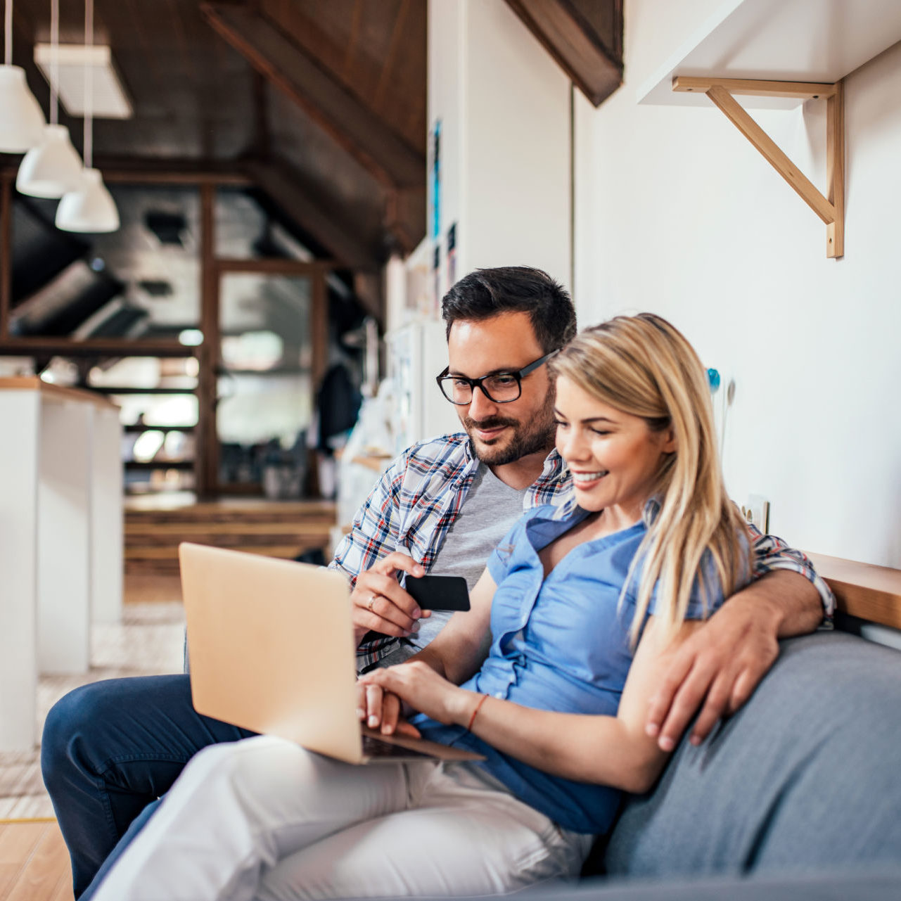 a couple sits on their couch researching the benefits of debt consolidation for high-interest credit card debt