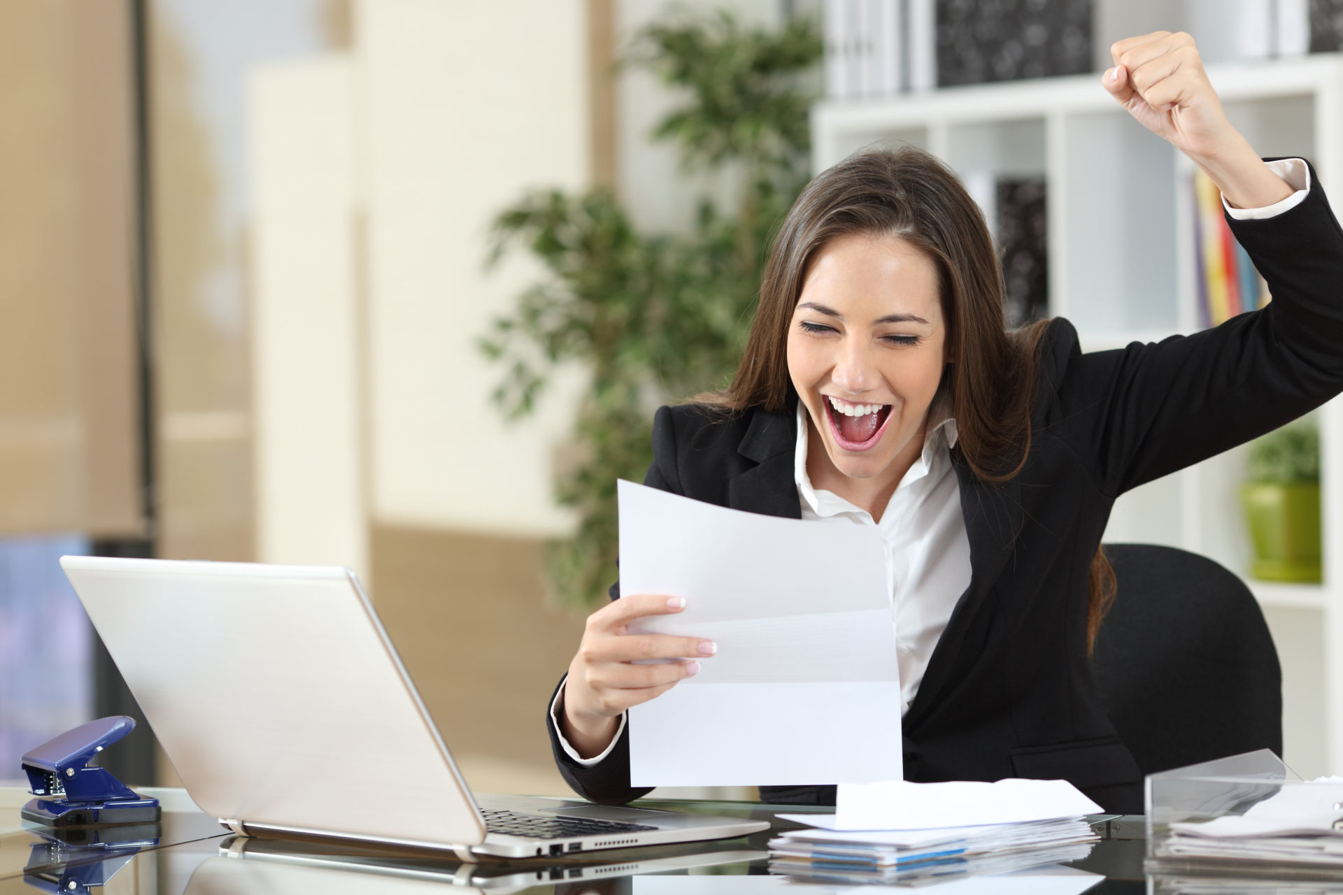 A young woman is in her office feeling excited to secure her finances with a personal line of credit.