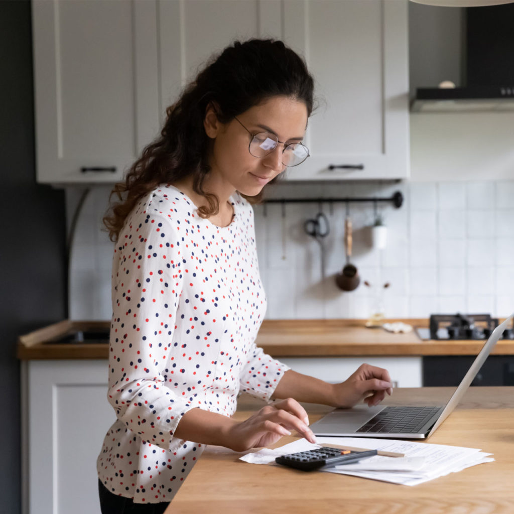 a woman calculates upcoming expenses and decides to apply for a personal loan vs. a personal line of credit in order to pay for them