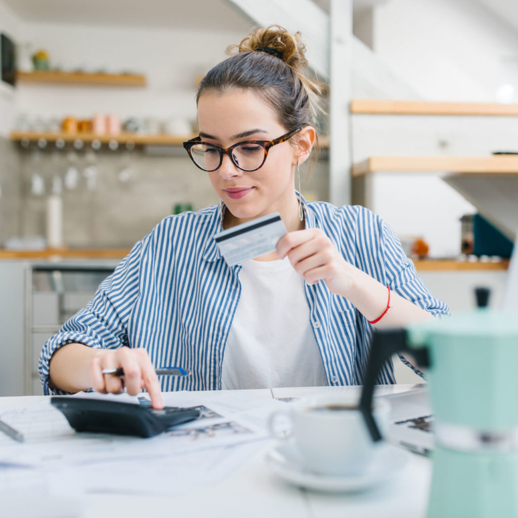 A young woman calculates her credit card payments and considers consolidating credit card debt.