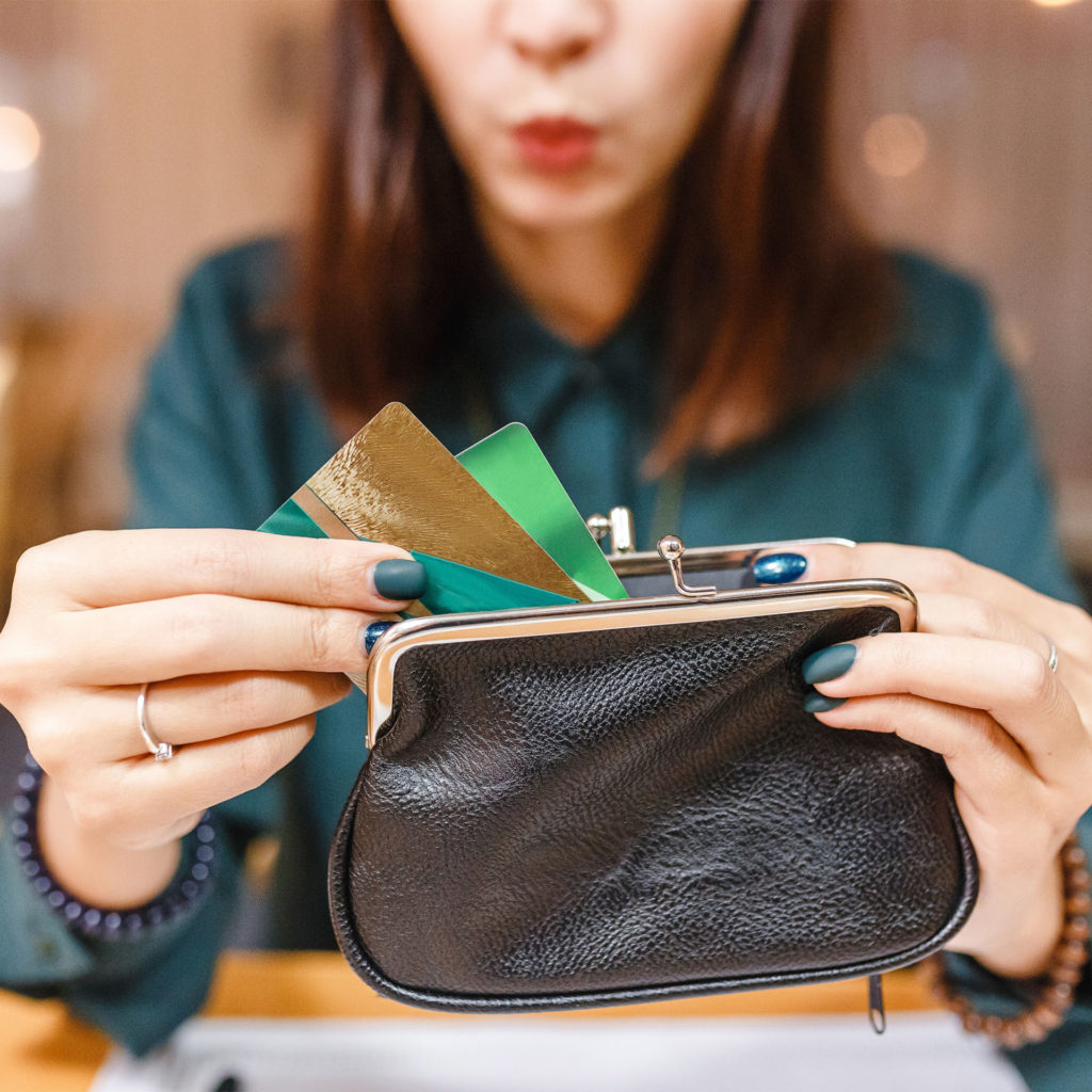 a woman pulls several cards out of her wallet and wonders if she should use her credit card for everything
