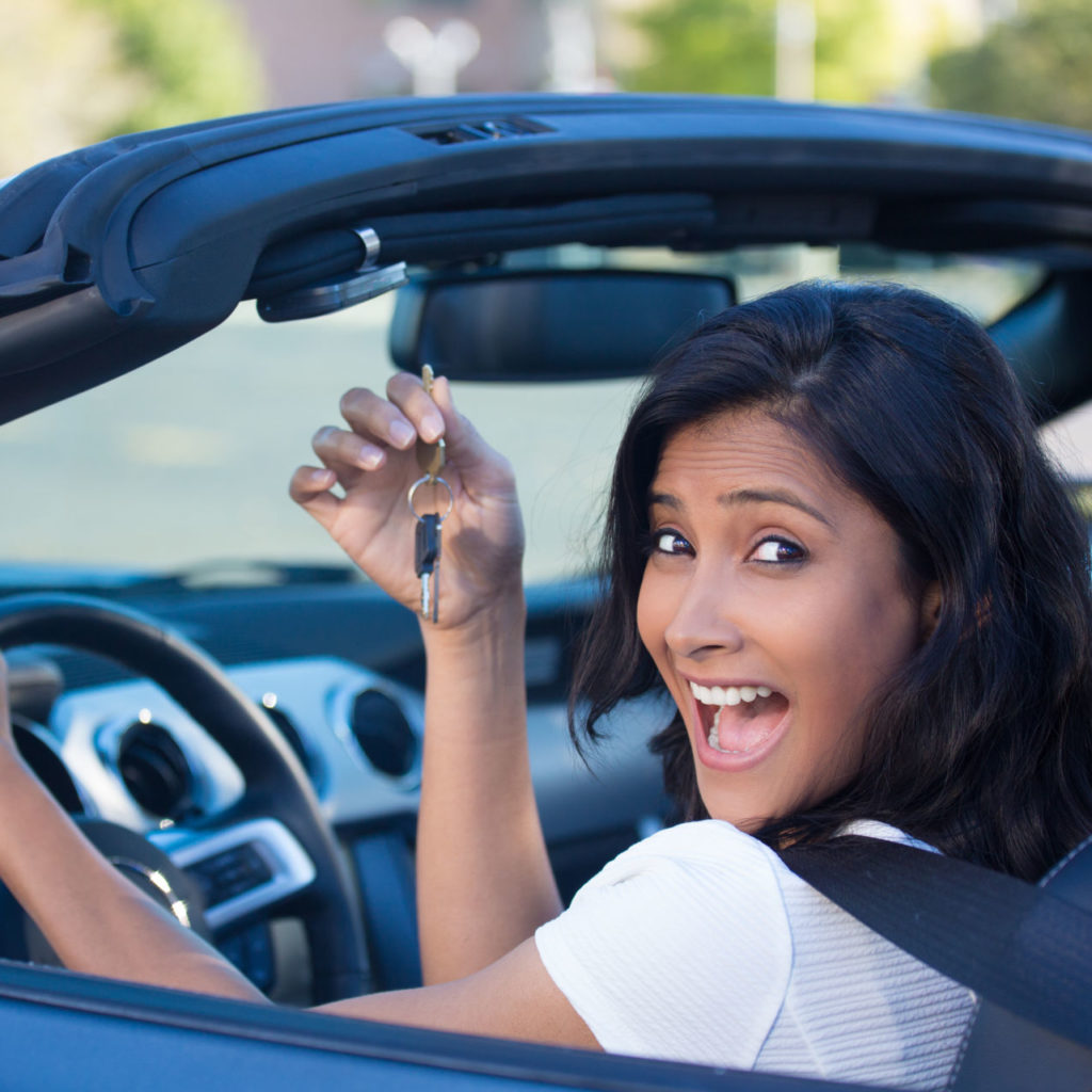 a woman smiles holding the keys to her new vehicle after getting pre-approved for an auto loan