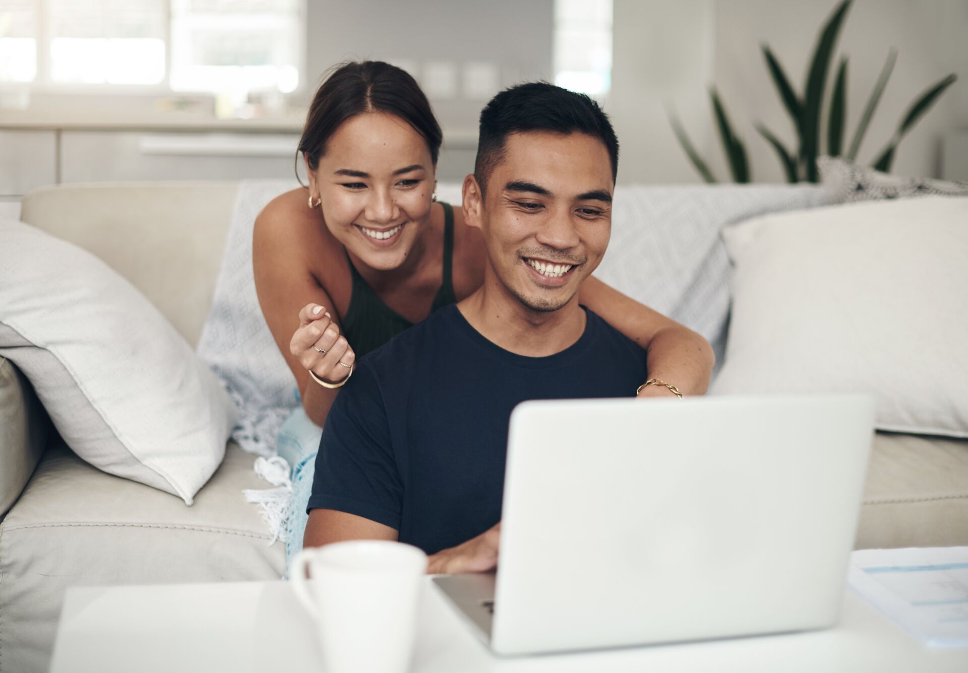 A young couple are happy about the savings progress they are making after checking their retirement accounts with online banking.
