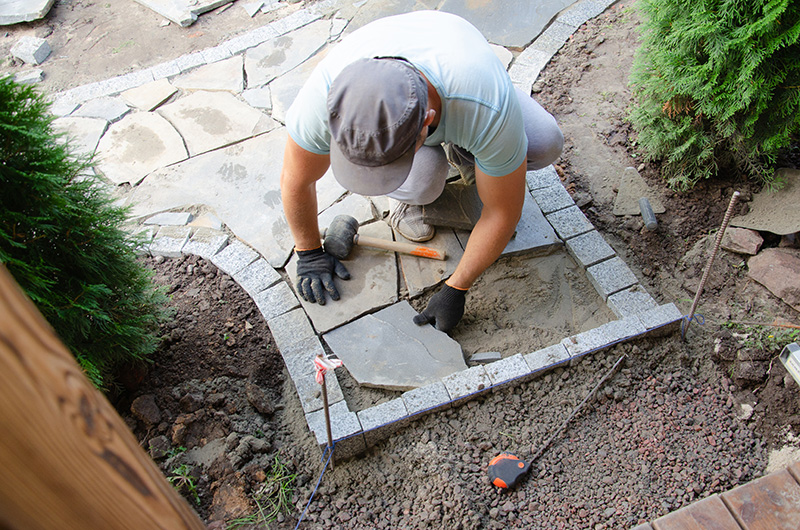 Construction of pavement near the house Bricklayer places concrete paving stone blocks for building up a Sidewalk pavement